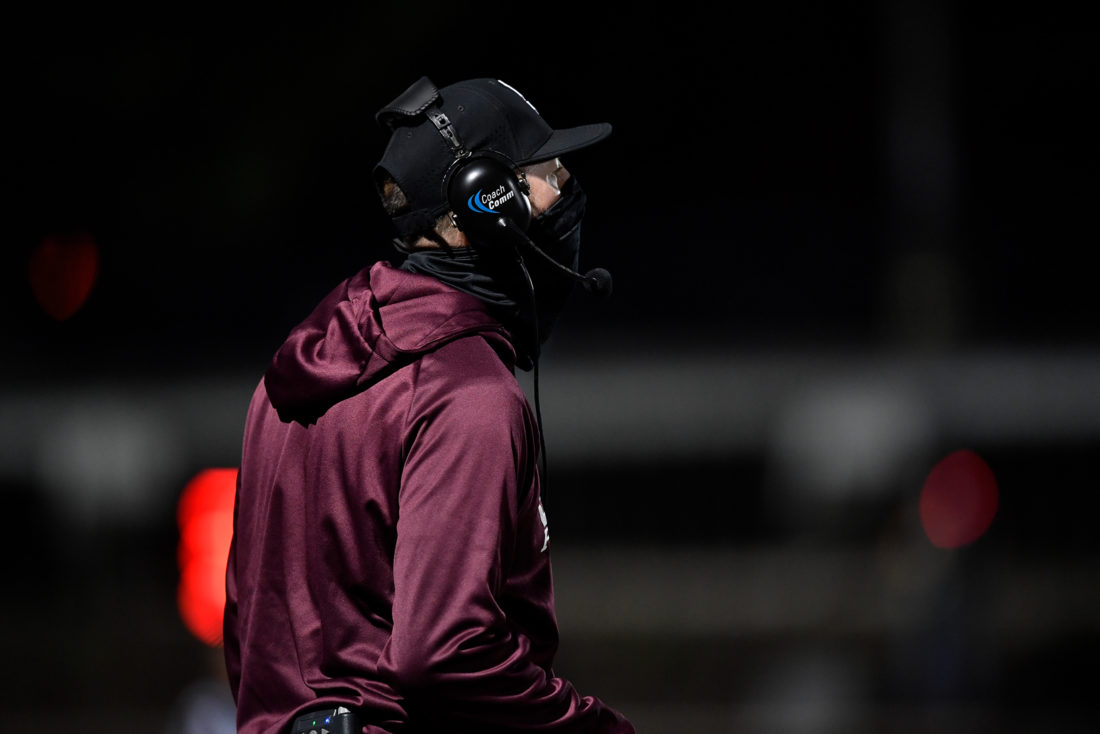 In a huddle, the Centralia Panthers lift their helmets after a